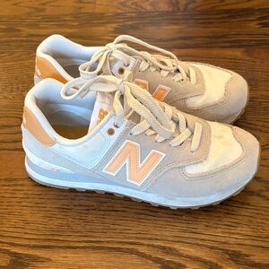 New Balance Women's 574 sneakers in the 'Timberwolf Alpha Orange' colorway.